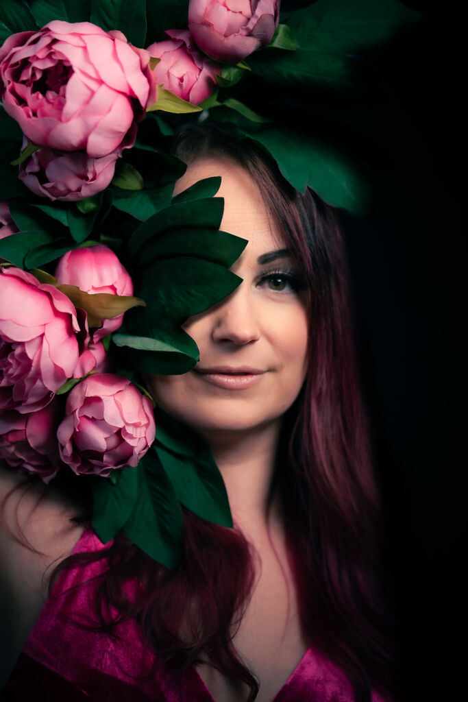 Pirita Niemenmaa salaperäisenä vaaleanpunaisten pionien takana.