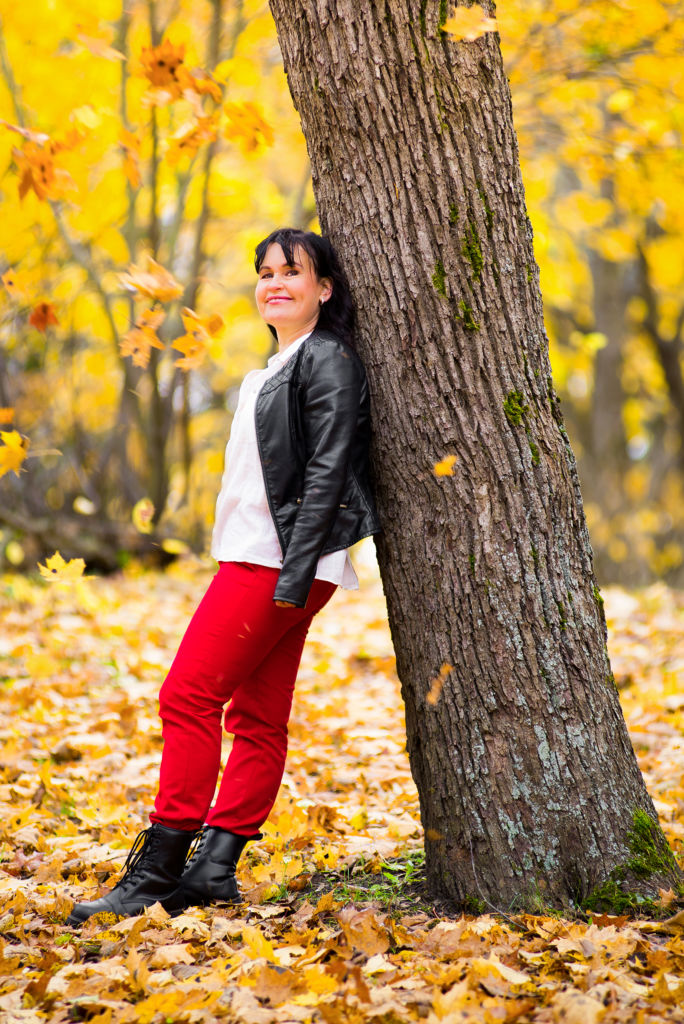Tuula Amberla nojaa puuhun syksyisissä maisemissa.